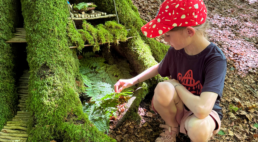 Mädchen bastelt eine Zwergenhütte im Wald