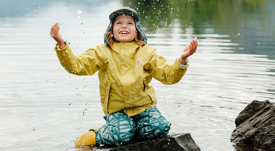 Kind in Regenbekleidung spielt im Wasser