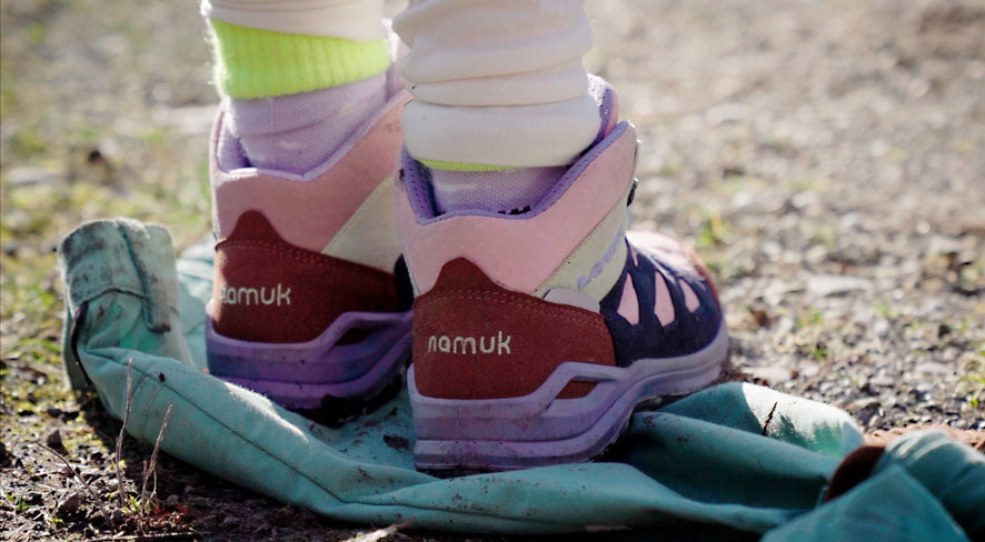 Kind steht mit Wanderschuhen auf namuk Hose