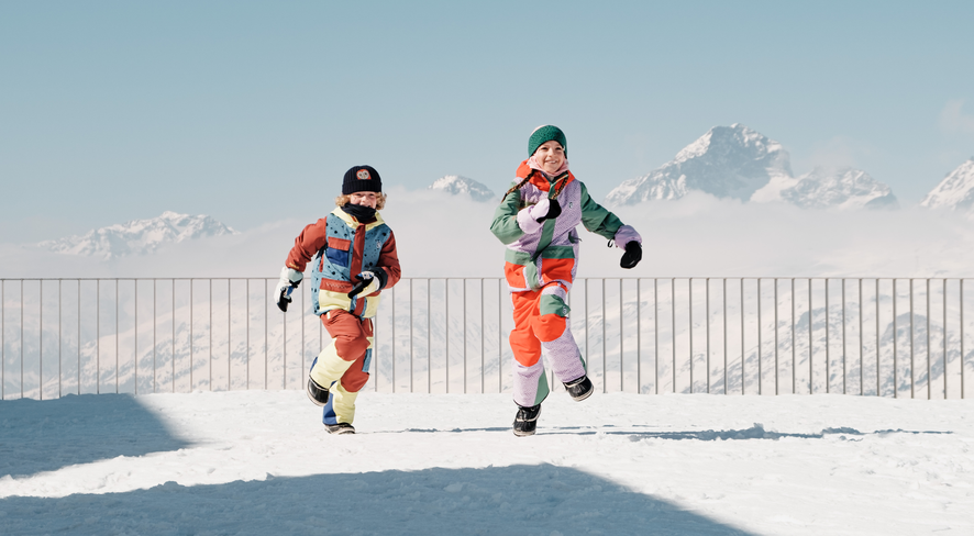 namuk Studie - Schweizer Kinder und Outdoor-Zeit - Zwei Kinder rennen durch den Schnee vor einer Bergkulisse