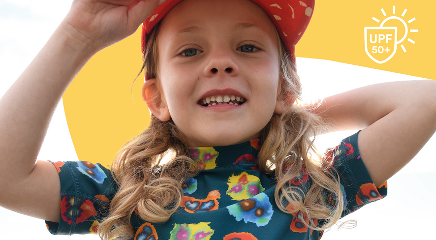 Kind in Badekleidung blickt fröhlich in die Kamera