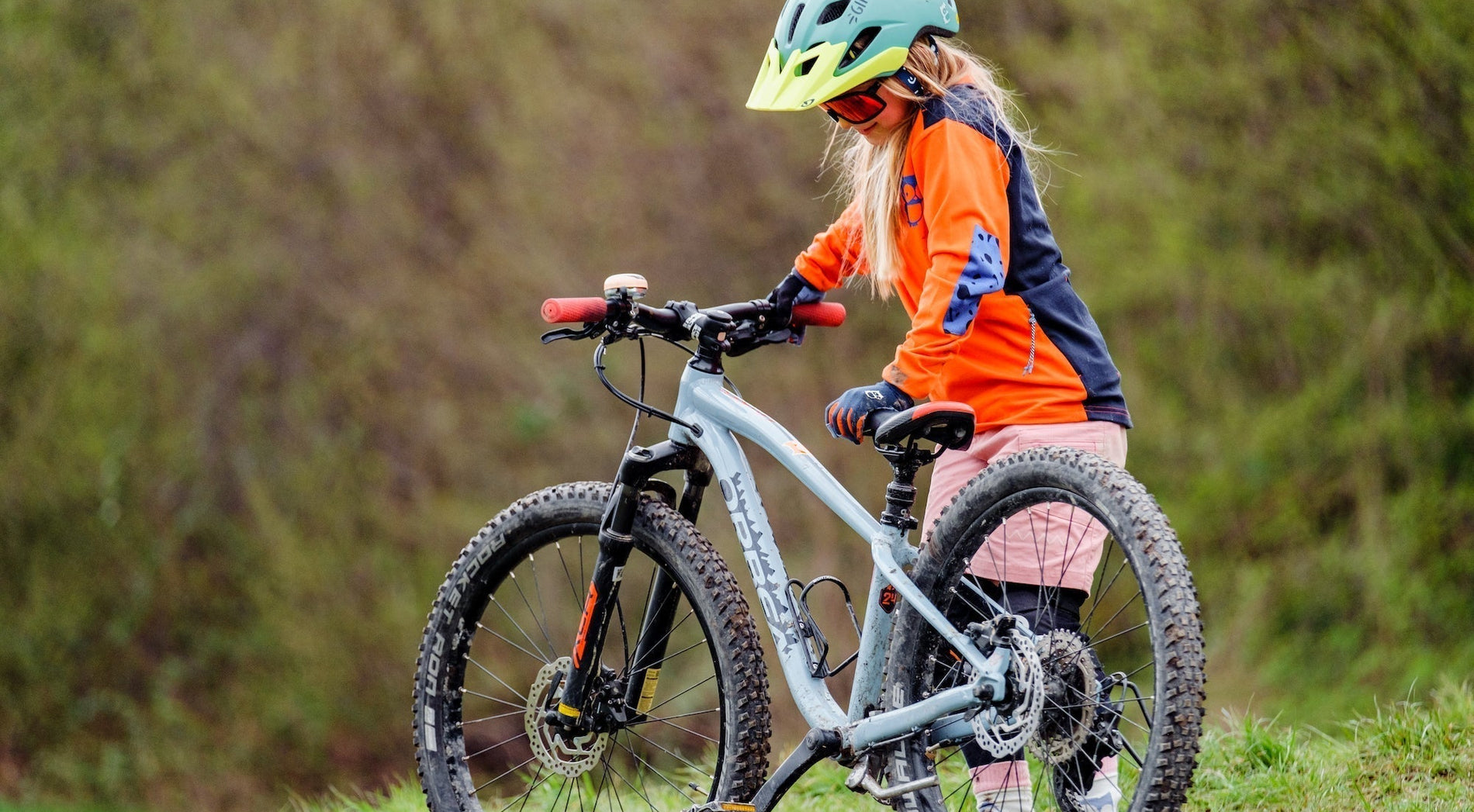 Fahrradtouren mit Kindern - Kind steht mit Fahrrad auf Wiese