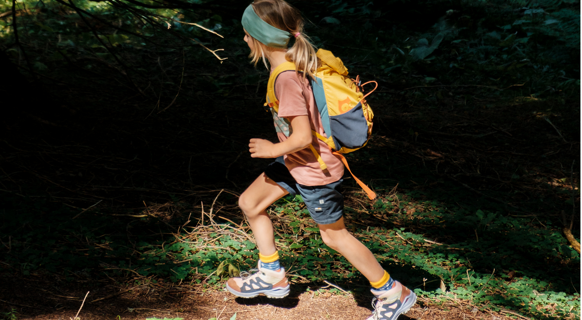 Wandern mit Kindern - Ein Mädchen wandert in namuk Kleidung und mit namuk Rucksack durch den Wald