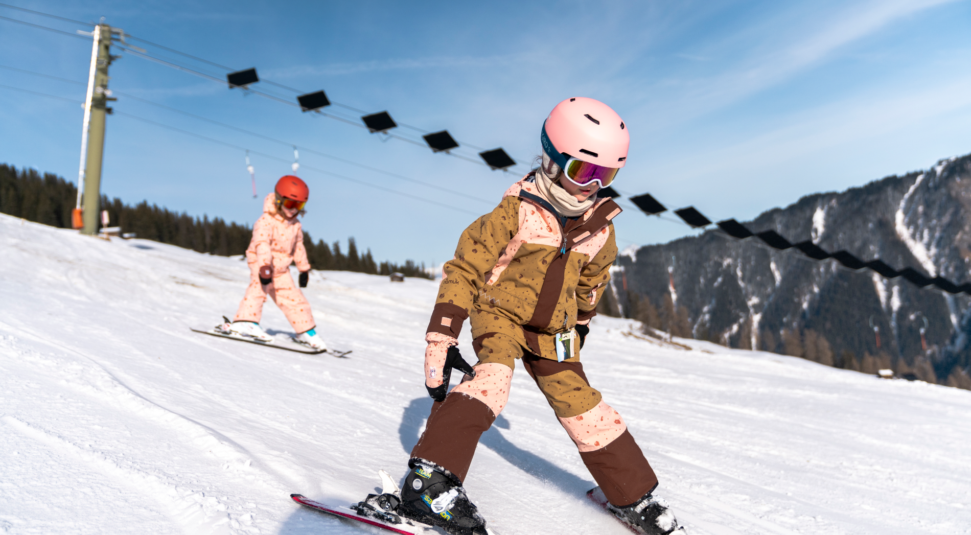 Zwei Kinder fahren Ski vor dem ersten solarbetriebenen Skilift in Tenna
