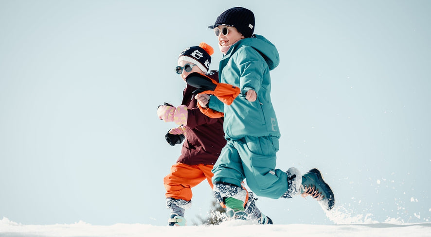 Kinder in namuk Skibekleidung rennen durch den Schnee